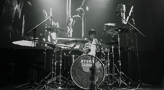 grayscale photo of man playing drum thumbnail