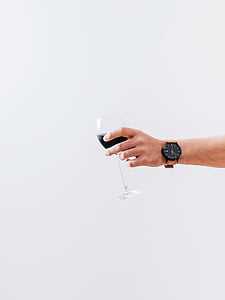 person holding clear wine glass with black liquid thumbnail