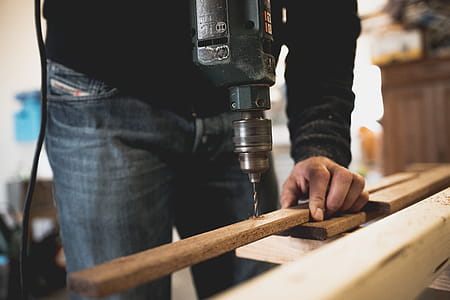 Man Holding Wooden Stick While Drilling Hole thumbnail