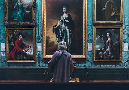 woman looking at paintings on wall inside well lit room thumbnail