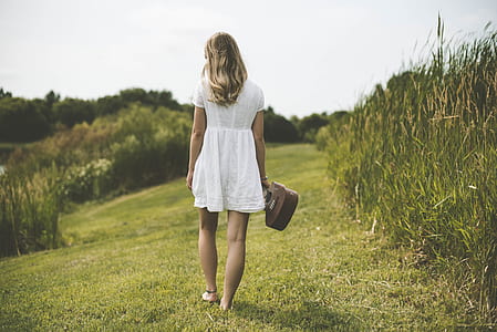 woman walking in grass field thumbnail
