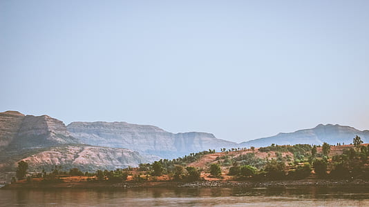green trees on mountain near body of water thumbnail