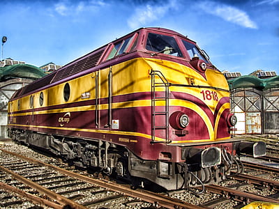 red and yellow train on rail under blue calm sky thumbnail