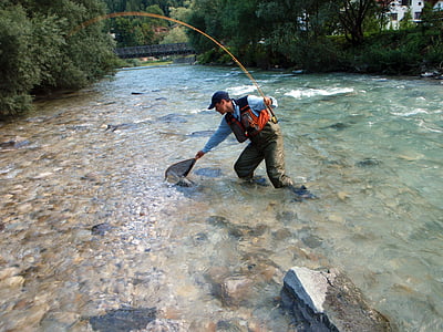 man holding net catching fish on lake thumbnail