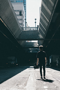 man walking underneath grey building thumbnail