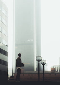 man standing near two post lamps near wall curtain building thumbnail