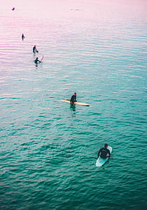 group of people surfing board surrounding by body of water thumbnail