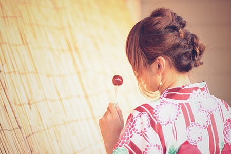 woman in white and brown floral dress holding lollipop thumbnail