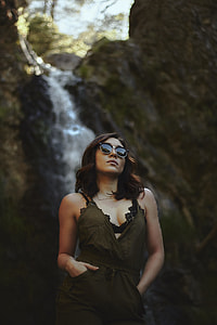 woman wearing black sunglasses, black scooped neck dress near in waterfalls during day time thumbnail