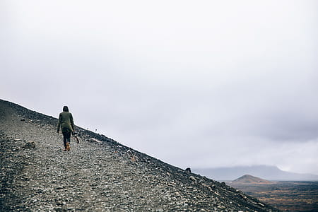 A hiker carrying a camera on a gravel hill thumbnail