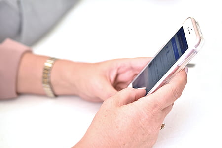person holding turned-on rose gold iPhone 6 while leaning on table thumbnail