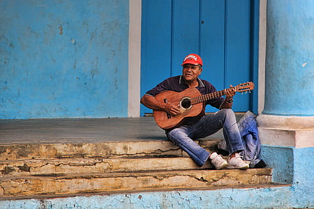man wearing black polo shirt sitting on stairs while playing acoustic guitar thumbnail