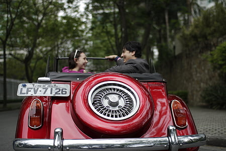 couple riding classic red convertible coupe during daytime thumbnail