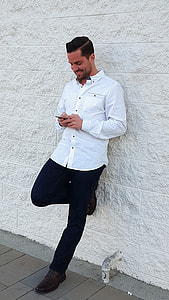 man wearing black and white dotted sport shirt holding Android smartphone thumbnail