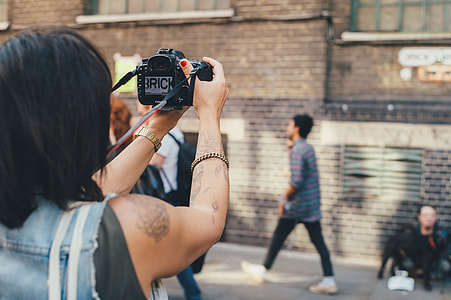 person holding camera in front of building thumbnail