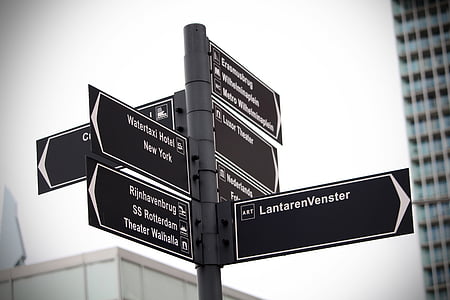 multiple black and white street signs on street pole thumbnail