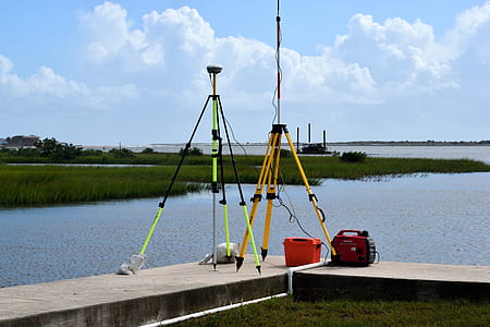 two orange, black, and green tripods beside body of water thumbnail