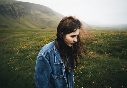 Woman Wearing Blue Denim Jacket Walking on the Green Grass Field thumbnail