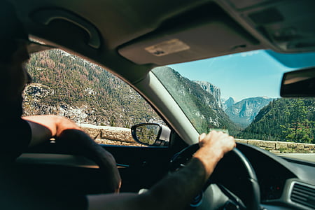 man driving vehicle on road across mountains during daytime thumbnail