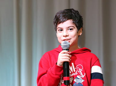 boy wears red hoodie and holds talking white holding black microphone thumbnail