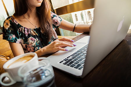 woman in black and multicolored floral shirt using MacBook while sitting thumbnail