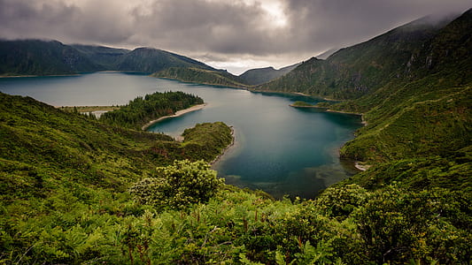 body of water surrounded by green mountains thumbnail