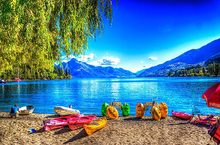 assorted-color kayak and boat near body of water background of mountains thumbnail