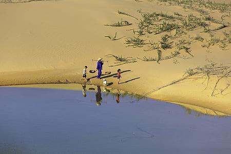 aerial photography of man wearing two kids beside river at daytime thumbnail