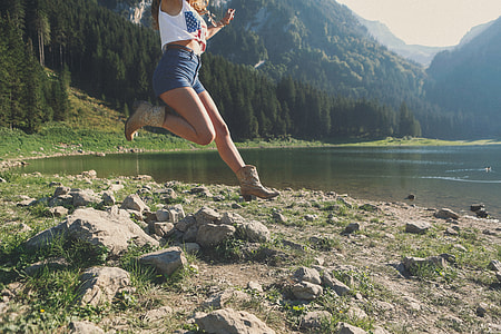 woman wearing white crop top jumping over rocks thumbnail