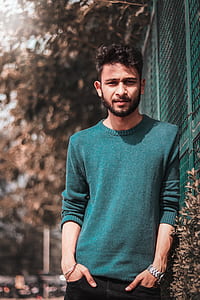 man standing near mesh fence with hands on pocket thumbnail