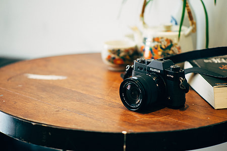 black Fujifilm SLR camera on top of brown table thumbnail