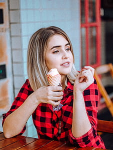 woman holding coned ice cream while sitting on chair inside room thumbnail