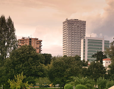 high rise building surrounded by green trees thumbnail