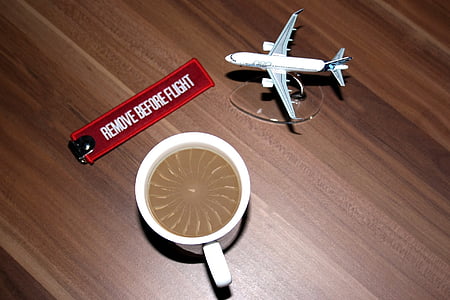white airliner toy beside teacup on brown wooden surface thumbnail
