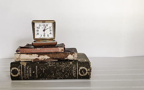 brown analog clock with books thumbnail
