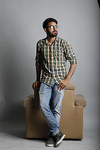 man in white and grey checked dress shirt leaning on brown armchair thumbnail