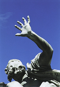 low-angle photo of concrete male raising hand statue under blue sky thumbnail