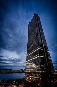 high-rise building with glass windows near body of water thumbnail