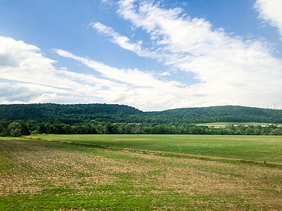 landscape photography of farm land under white clouds and blue sky thumbnail