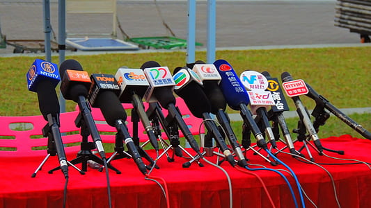 assorted-brand microphones leaning on microphone stands on red cloth table thumbnail