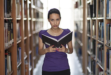 woman in purple top holding book in library thumbnail