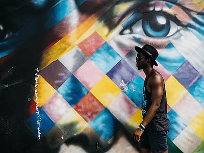 man wearing grey tank top and black hat walking across eye wall paint thumbnail