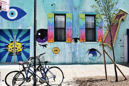 two assorted-color bikes leaning on brown metal pole beside building thumbnail