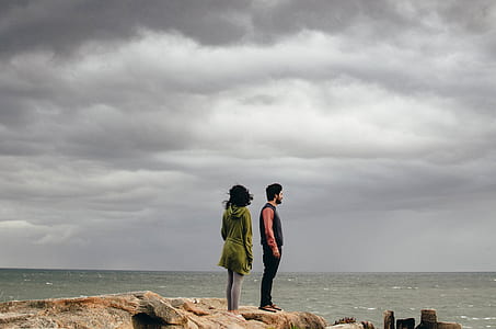 landscape photography of man and woman facing body of water thumbnail