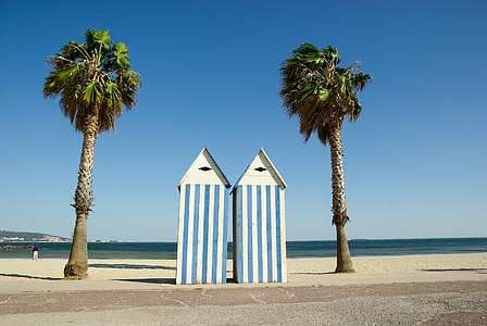two white-and-blue striped sheds between two palm trees thumbnail