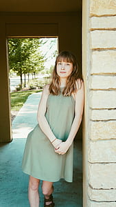woman in green dress leaning on wall thumbnail