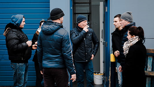 seven people talking to each other near open door thumbnail