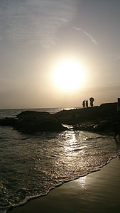 silhouette of three people on cliff over body of water during night time thumbnail