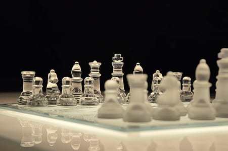 Clear Glass and White Chess Piece on White Chess Board With Black Background thumbnail