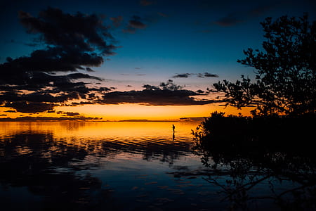 silhouette person standing on body of water thumbnail